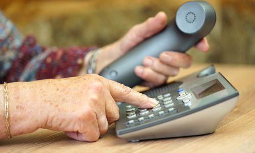 closeup of old female hands dialing a telephone number